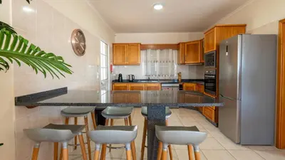a kitchen with a counter with stools and a refrigerator at Casa Del Sol by LovelyStay in Relógio do Poiso