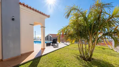 a palm tree in a yard next to a house at Casa Del Sol by LovelyStay in Relógio do Poiso