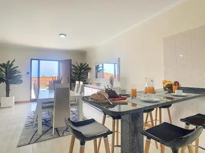 a kitchen with a island with chairs and a table at Casa Mes Amis by LovelyStay in Relógio do Poiso