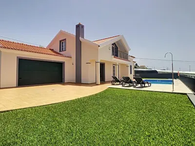 a house with a garage with a grass yard at Casa Mes Amis by LovelyStay in Relógio do Poiso