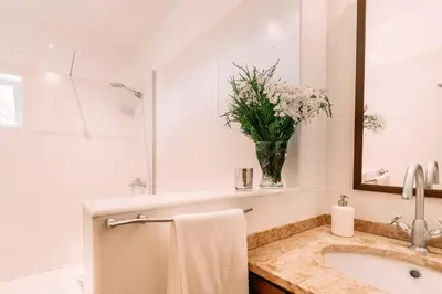 a white bathroom with a sink and a vase of flowers at Atlantic View Penthouse in Funchal