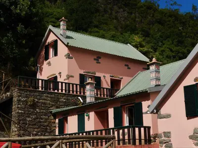 a pink house with a green roof at Casinhas da Laurissilva in São Vicente