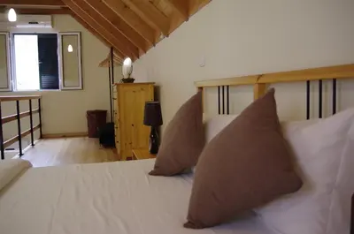 a bedroom with a bed with white sheets and pillows at Casinhas da Laurissilva in São Vicente