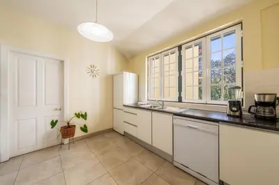 a kitchen with white cabinets and a large window at The Wine Lodges by An Island Apart in Funchal
