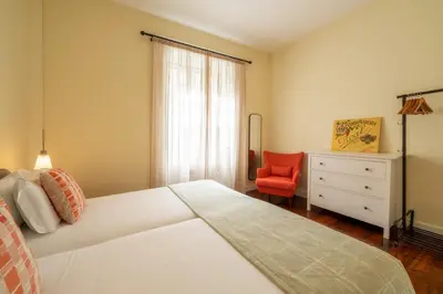 a bedroom with a white bed and a red chair at The Wine Lodges by An Island Apart in Funchal