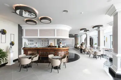 a restaurant with a bar with white chairs and tables at Hotel Riu Madeira - All Inclusive in Caniço