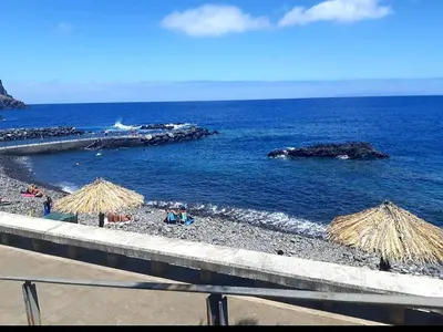 a beach with some straw umbrellas and the ocean at Apartamento Marques in Santa Cruz