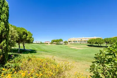 a golf course with trees and a building in the background at Casa Mapie - Boavista Resort in Lagos