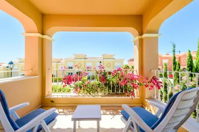 a porch with two chairs and a table and flowers at Casa Mapie - Boavista Resort in Lagos