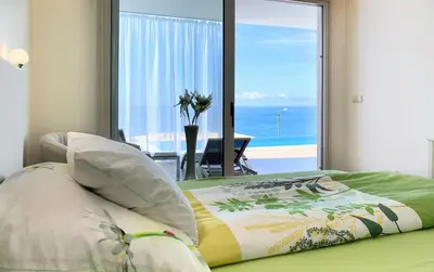 a bedroom with a bed with a view of the ocean at Holiday Apartment Sunset Ocean in Ribeira Brava