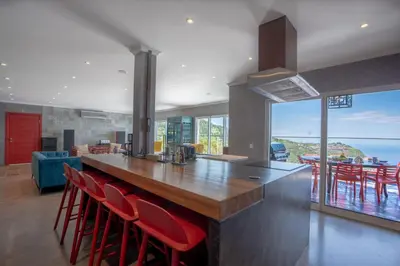 a kitchen with a large counter with red chairs at Mansão Macau by LovelyStay in Arco da Calheta