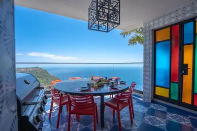 a table and chairs on a balcony with a view of the ocean at Mansão Macau by LovelyStay in Arco da Calheta