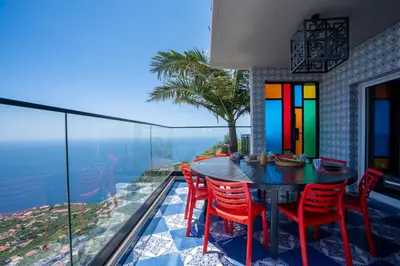 a dining room with a table and chairs on a balcony at Mansão Macau by LovelyStay in Arco da Calheta