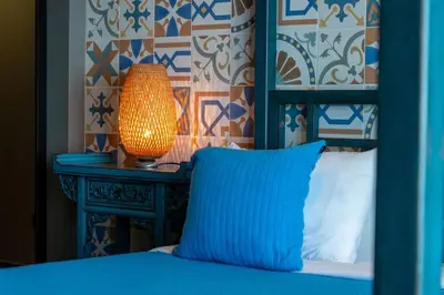 a bed with a blue headboard and a lamp on a table at Mansão Macau by LovelyStay in Arco da Calheta