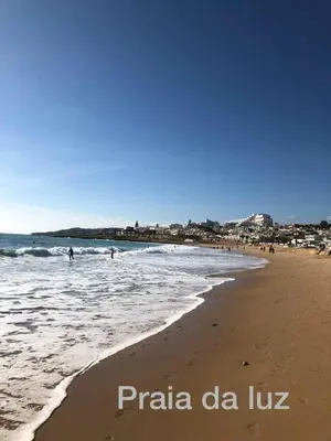 a beach with people in the water and people in the ocean at LUXURY APARTMENT - T1 vue sur piscine - PRAIA DA LUZ in Luz