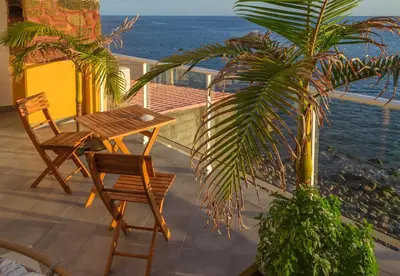 a patio with a table and chairs and a palm tree at maktub sunset property in Paul do Mar