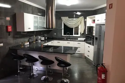 a kitchen with black counter tops and black stools at Ammy’s House in Câmara de Lobos