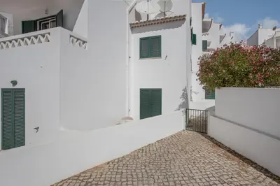 a white house with green shutters and a sidewalk at Refúgio Na Praia Da Luz in Luz