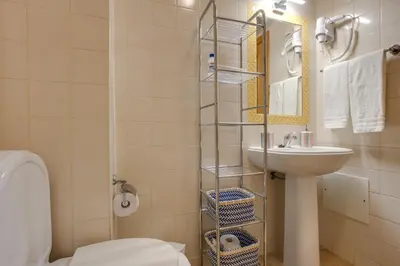 a bathroom with a sink and a toilet and a mirror at Refúgio Na Praia Da Luz in Luz
