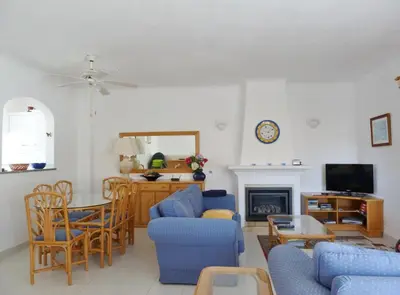 a living room with blue chairs and a fireplace at Casa Rosa Floresta in Luz