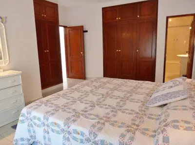 a bedroom with a bed and wooden cabinets at Casa Rosa Floresta in Luz