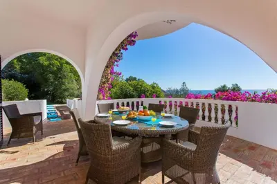 a patio with a table and chairs and flowers at Casa dos Cardos in Luz