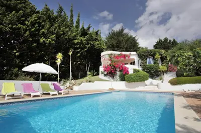 a swimming pool with chairs and a house at Casa dos Gemeos in Luz