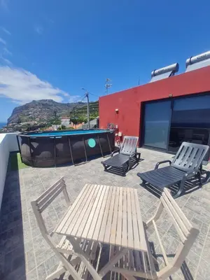 a patio with three chairs and a table and a pool at GuestReady - Sonho dos Avós in Câmara de Lobos