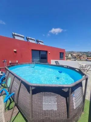 a large blue swimming pool in front of a red building at GuestReady - Sonho dos Avós in Câmara de Lobos