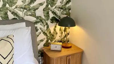 a lamp on a night stand next to a bed at Madeira Mero Apartment in Caniço