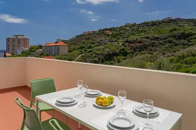 a white table with a bowl of fruit on a balcony at Reis Magos V by An Island Apart in Caniço