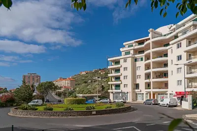 a large white building with a hill in the background at Reis Magos V by An Island Apart in Caniço