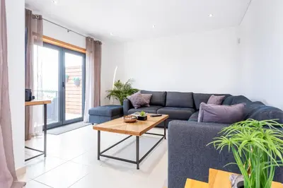 a living room with a blue couch and a table at Casa Chic in Vila do Bispo