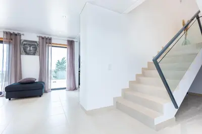 a white staircase in a living room with a black chair at Casa Chic in Vila do Bispo