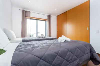 a bedroom with two beds and a large window at Casa Chic in Vila do Bispo