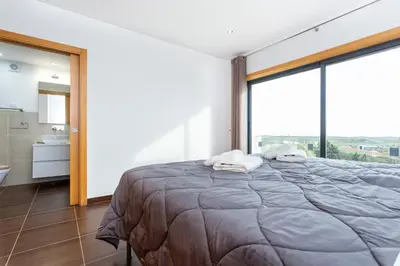 a bedroom with a large bed and a large window at Casa Chic in Vila do Bispo