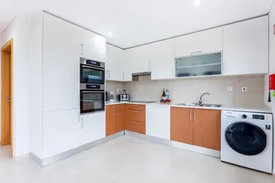 a kitchen with white cabinets and a washer and dryer at Casa Chic in Vila do Bispo