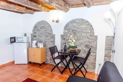 a kitchen and dining room with a table and two arches at Refúgio do Vale in Ribeira Brava