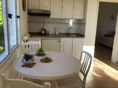 a small kitchen with a white table and chairs at Bungalows Do Amparo in Ponta do Pargo