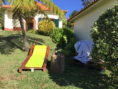 a garden with a bench and a chair and a house at Bungalows Do Amparo in Ponta do Pargo