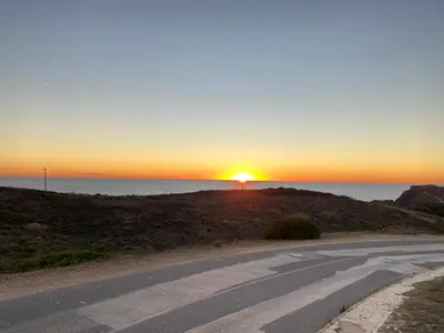 an empty road with the sunset in the background at Arrifana Beach Break in Aljezur