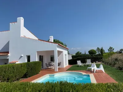 a villa with a swimming pool in front of a house at Casa Colina, walking distance to Arrifana Beach in Aljezur