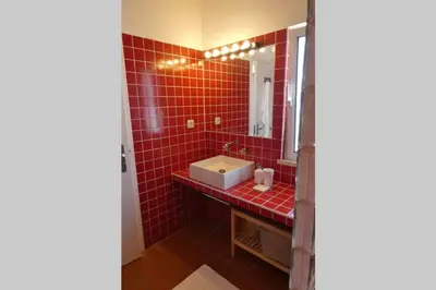 a red tiled bathroom with a sink and a mirror at Casa Colina, walking distance to Arrifana Beach in Aljezur