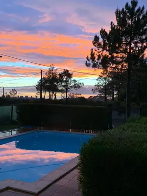 a blue swimming pool with a sunset in the background at Casa Colina, walking distance to Arrifana Beach in Aljezur