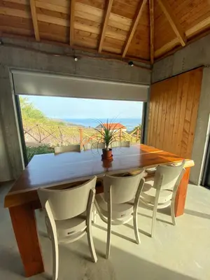 a dining room with a table and chairs and a large window at Casa Pereirinha in Estreito da Calheta