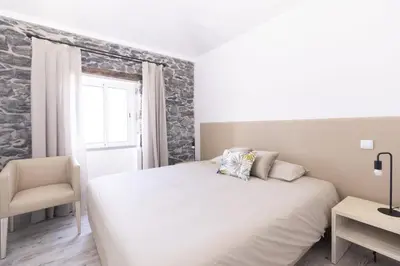 a bedroom with a bed and a chair and a window at Stay in our cozy and wonderful Casa da Rosinha in Arco da Calheta