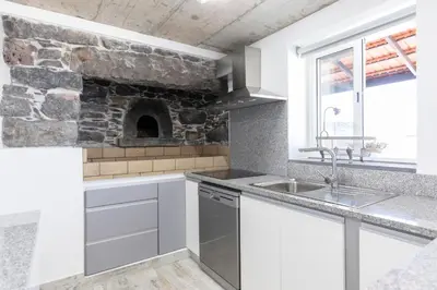 a kitchen with a sink and a stone fireplace at Stay in our cozy and wonderful Casa da Rosinha in Arco da Calheta