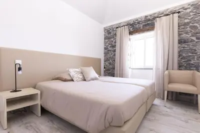 a white bedroom with a bed and a chair at Stay in our cozy and wonderful Casa da Rosinha in Arco da Calheta