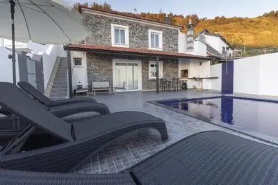 a house with a swimming pool with chairs and an umbrella at Stay in our cozy and wonderful Casa da Rosinha in Arco da Calheta