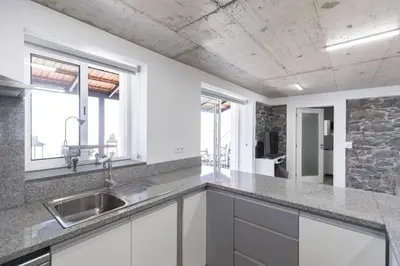 a kitchen with white cabinets and a sink and windows at Stay in our cozy and wonderful Casa da Rosinha in Arco da Calheta